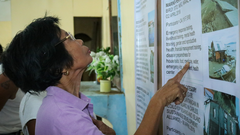Elderly woman reading printed material on the wall