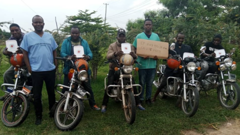 Dr. Deus Kitapondya, an emergency medicine physician in Dar es Salaam and co-founder of the Okoa Maisha Initiative, stands  with one of the first groups of bodaboda drivers in Tanzania to undergo basic bleeding control training in 2022