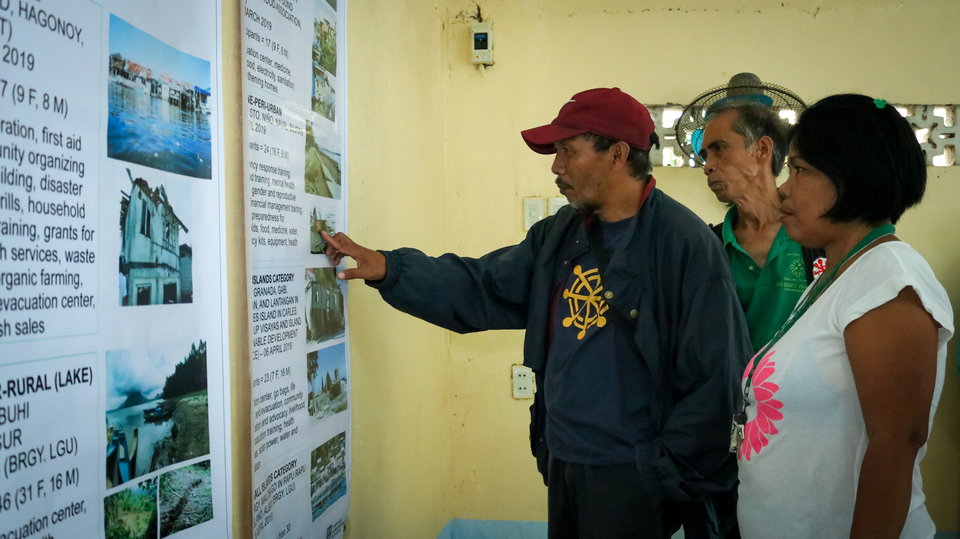 Local leaders in a Philippine community reading HHI's printed learning product